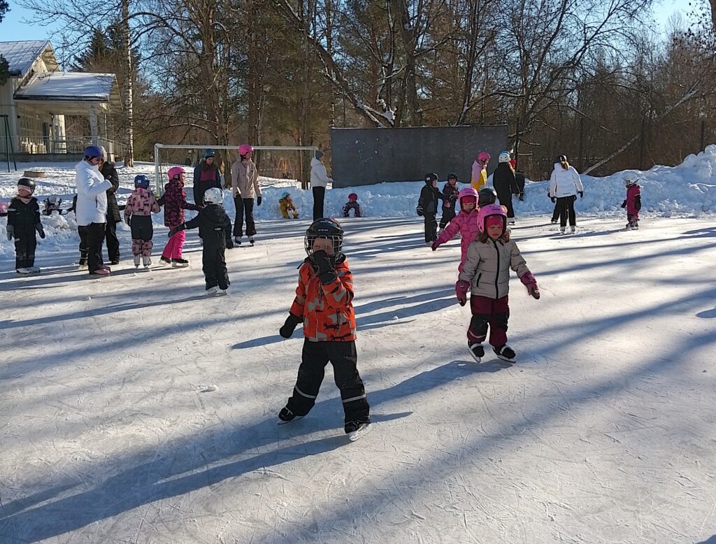 Koululaisia luistelemassa jäädytetyllä ulkokentällä.