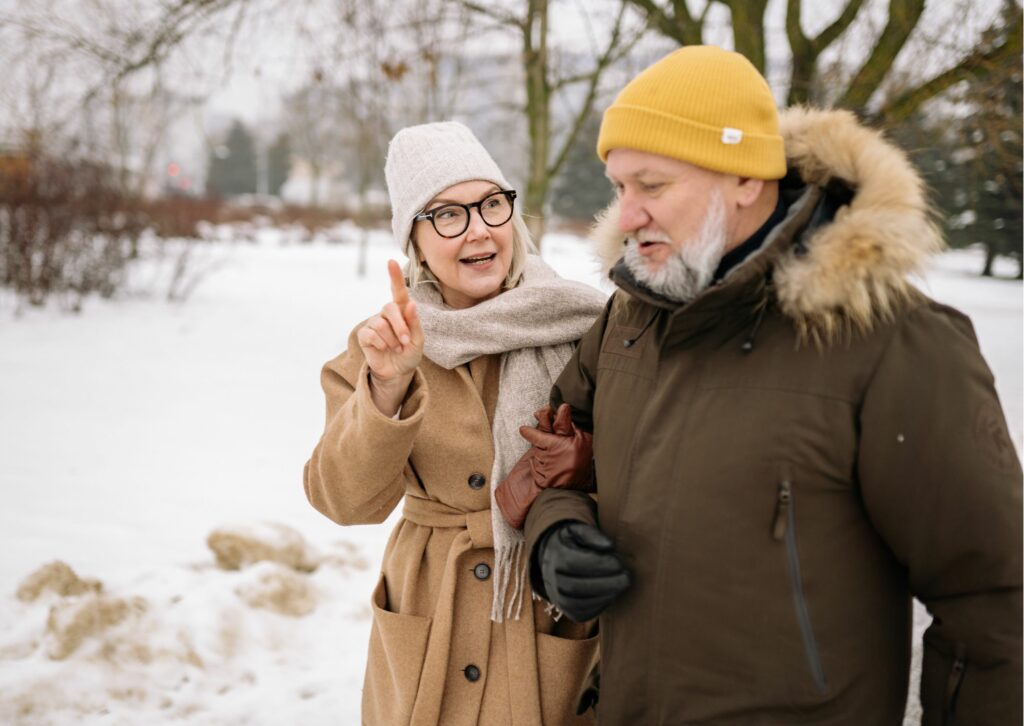 Eläkeläisparikunta kävelyllä talvisäällä ulkona.